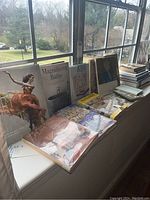 Books displayed on a windowsill showing titles including The Art of Movement, Magnificent Baths, Art of Her Own, Leonardo, and others stacked