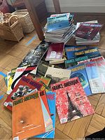 Overview of the magazines and books spread on the floor, showing multiple France-Amerique magazines and Parisian literature books.