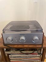 Front view of silver Jensen turntable showing three large control knobs and transparent dust cover closed.