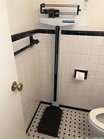 Full view of Health-O-Meter Professional standing scale positioned in a tiled bathroom corner, showing white body with black base platform and height rod.