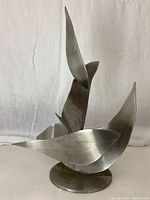 Front view showing curved abstract fish shapes and circular base.