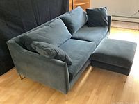Angled view of blue sofa and ottoman on hardwood floor