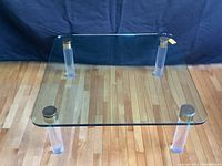 Full view of square glass-top coffee table with four lucite legs
