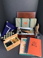 Overview photo showing games including chess board, cribbage board with pegs, 76 flag, two books, and a decorative carved wood sculpture