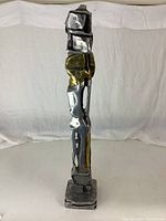 Full front view of tall abstract metal sculpture on square base