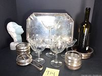Cartier silver plate bar tray with geometric corners, glass coasters with sterling silver rims, silver plate wine bottle coaster with monogram, crystal coupes, silver sugar tongs, and Marti bust arranged for display