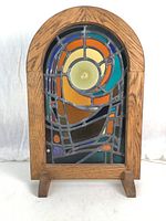 Front view of stained glass window pane in oak arch frame and stand