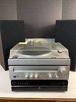 Full lot view: turntable with dust cover on top of receiver and CD changer, speakers behind, records displayed