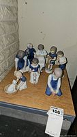 Group photo of nine Bing & Grondahl porcelain figurines of children with animals arranged on wooden surface.