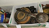 Box containing two cast iron frying pans, ladle and individual round molds