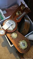 Two wooden plaques each fitted with three brass nautical instruments (barometers, thermometers, hygrometers)