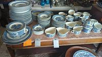 Multiple stacks of blue and white transferware plates, soup bowls, saucers, mugs, gravy boats and ashtrays on table