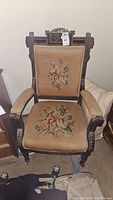 Full view of the vintage wooden armchair showing floral needlepoint embroidery on seat and backrest.