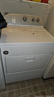 Front view of white Whirlpool dryer with control panel and closed door