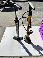 Photo showing both air pumps standing on a white surface outdoors, displaying the overall condition and appearance of the pumps.