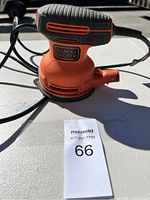 Photo of Black & Decker orange and black orbital sander sitting on a light-colored surface with power cord visible.