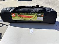 Full view of the black carrying bag with a label showing the red padded hammock and frame folded inside, placed on a table.