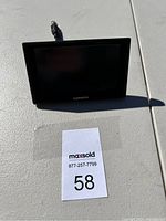 Garmin GPS device showing front and back with power/data cable attached, placed on a white surface with a MaxSold lot number tag.