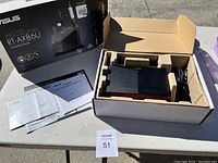 Open box containing the router, power cord, and manuals laid out on table.