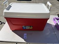 Red Igloo cooler with white top and handles on either side placed on table.