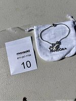 Full view of the Pandora bracelet with white pouch showing the bracelet and charms inside.