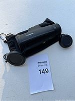 Photo of Phission monocular scope resting on black carrying pouch with lens covers extended.