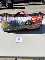 Coleman Skydome tent in bag showing brand, model name, and key features like Dark Room Technology and setup speed.