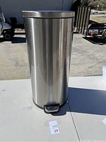 Front view of tall cylindrical metal trash can with foot pedal to open lid.