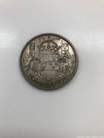 Reverse side of the 1954 Canadian 50 cent coin showing Canadian Coat of Arms and date.