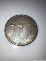 Reverse side of the 1967 Canadian Centennial Dollar coin featuring a flying Canada goose design and inscriptions.