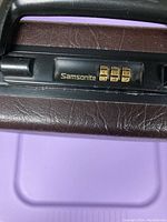 Close-up image of the Samsonite combination lock on the briefcase showing the brand name and combination dials.