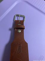 Close-up of the leather belt buckle area embossed with 'LEVIS' and shield logo.