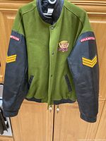 Front view of green and black jacket with Brampton Battalion patches and snap buttons
