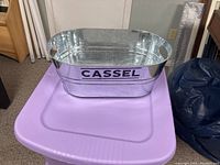 Metal ice bucket with 'CASSEL' branding on the outside, placed on a purple surface