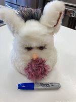 Photo showing full front view of the white Furby with purple beard and included Sharpie marker for size reference.