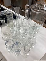 Clear glassware lot arranged on white surface including vases, decanters, and wine glasses.