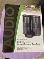 Boxed Centrios 900 MHz wireless indoor/outdoor speakers showing brand, model, and usage information.