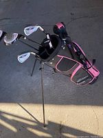 Full view of kids golf stand bag holding several golf clubs on concrete surface