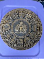 Front view of circular carved wooden RCMP plaque with provincial and territorial crests around the edge.