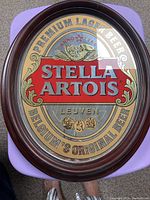 Oval wooden-framed mirror with Stella Artois Premium Lager Beer logo.