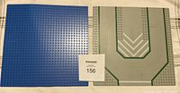 Two large LEGO baseplates side by side on a wooden floor with MaxSold tag 156. One blue baseplate and one grey baseplate with printed road design.