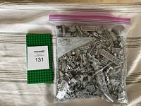 Green LEGO base plate next to bag of grey LEGO pieces