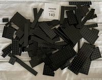 Photo of assorted black LEGO plates scattered on a white surface showing various sizes and shapes.