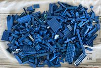 Pile of various blue LEGO pieces spread out on a white surface showing different sizes and flat plates