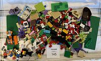 Top view of all assorted LEGO pieces and minifigures sorted together on a cloth surface.