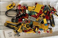 Top view of assorted LEGO pieces including treads, bricks, wheels, and miscellaneous parts