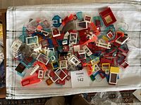 Overhead photo of a large assortment of LEGO window and door pieces, showing multiple colors and styles spread out on a cloth.