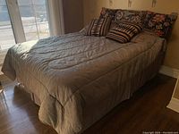 Full view of the bed made up with pillows and comforter on the bedframe, showing size and overall appearance.