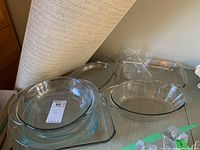 Set of five clear glass casserole and baking dishes arranged on a surface showing various round, oval and rectangular shapes.