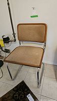 Side angle view of metal frame chair with upholstered seat and back in light brown corduroy fabric, showing chrome tubular frame and wood-like trim.
